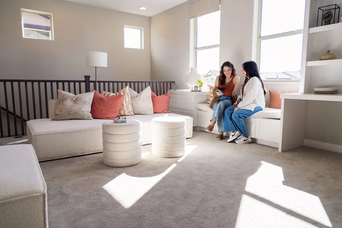 Mother and daughter sitting on window seat together talking