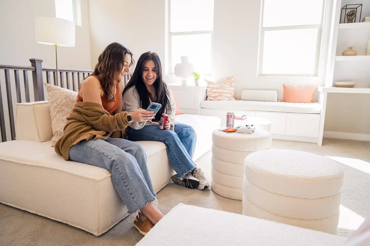 2 goirls on couch looking at cell phone