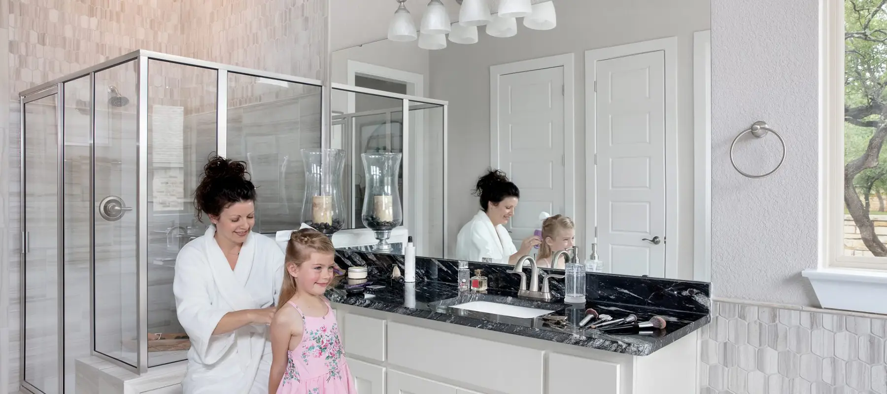 woman braiding daughters hait in bathroom